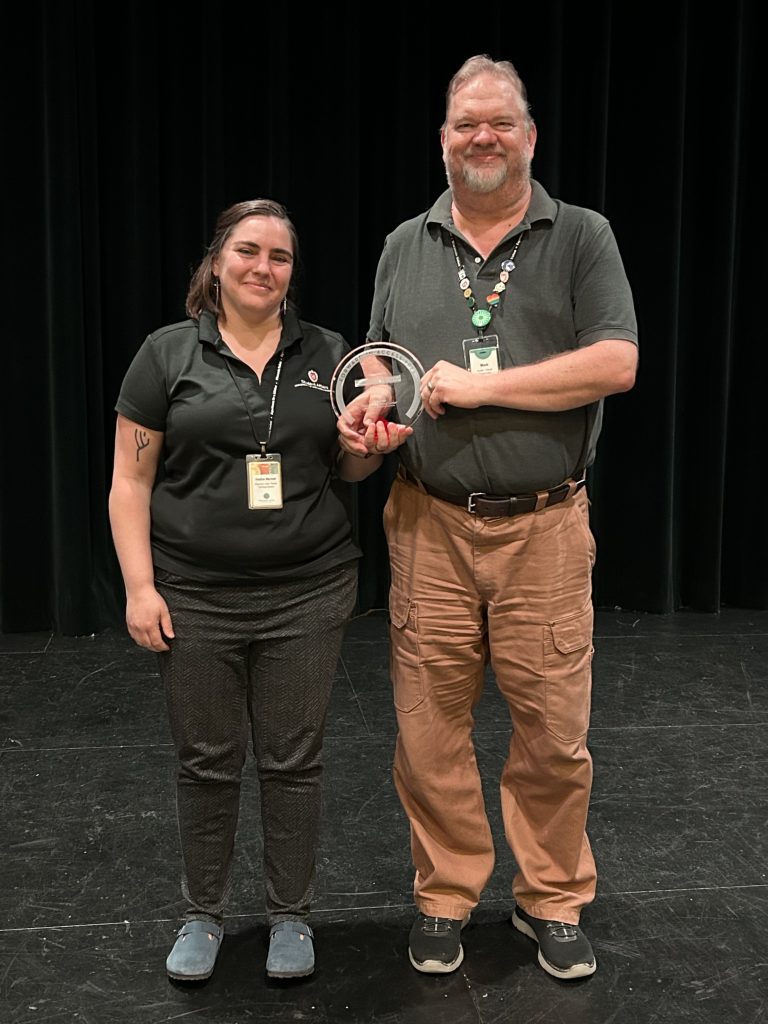 Heather Macheel and Mark Schappe with Forward and Access award on stage in the Memorial Union