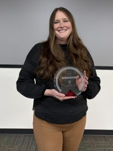 Ellen Cecil-Lemkin holding a Forward in Access award in a classroom